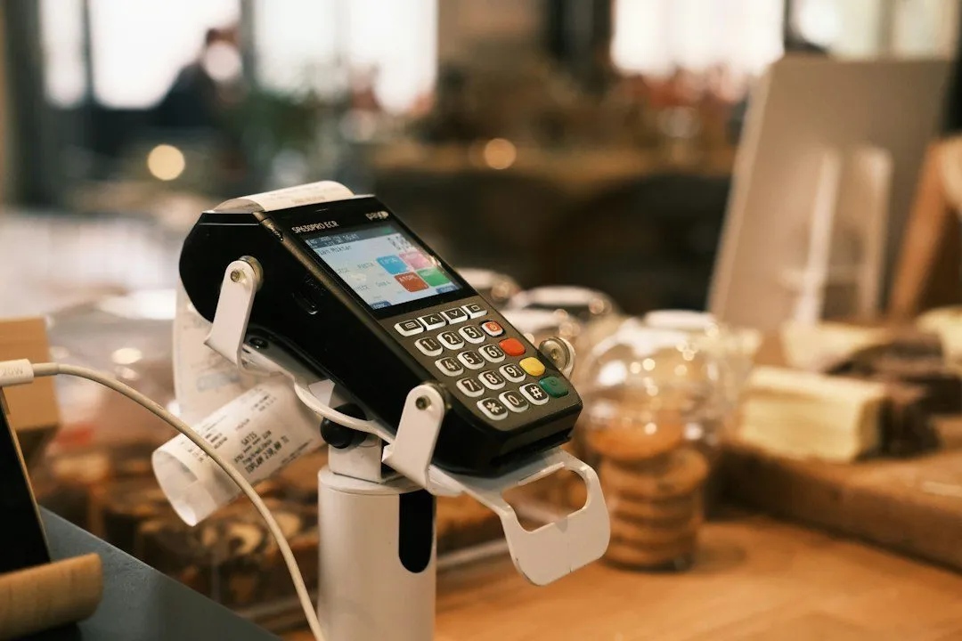 Datáfono en su soporte sobre el mostrador de una tienda, con el ticket de pago saliendo