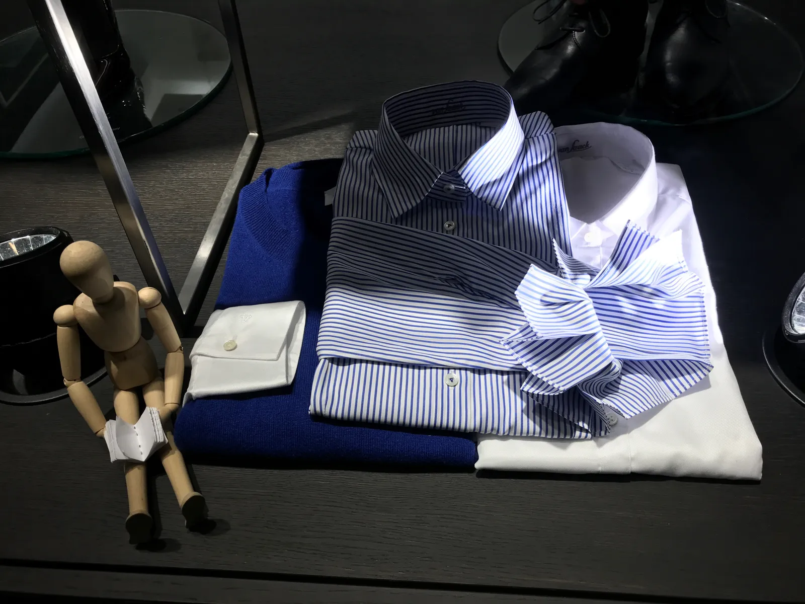 Mesa de producto con camisas dobladas, corbatas y gemelos en una tienda de moda masculina